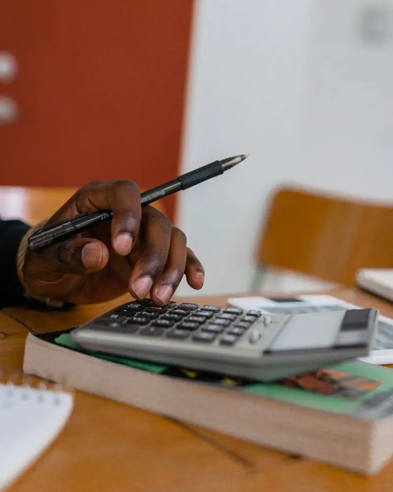 A hand with a pen working out figures on a calculator