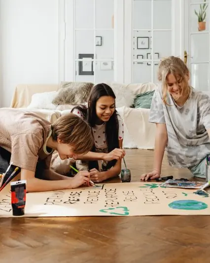 Teenagers painting a big project poster together on the floor