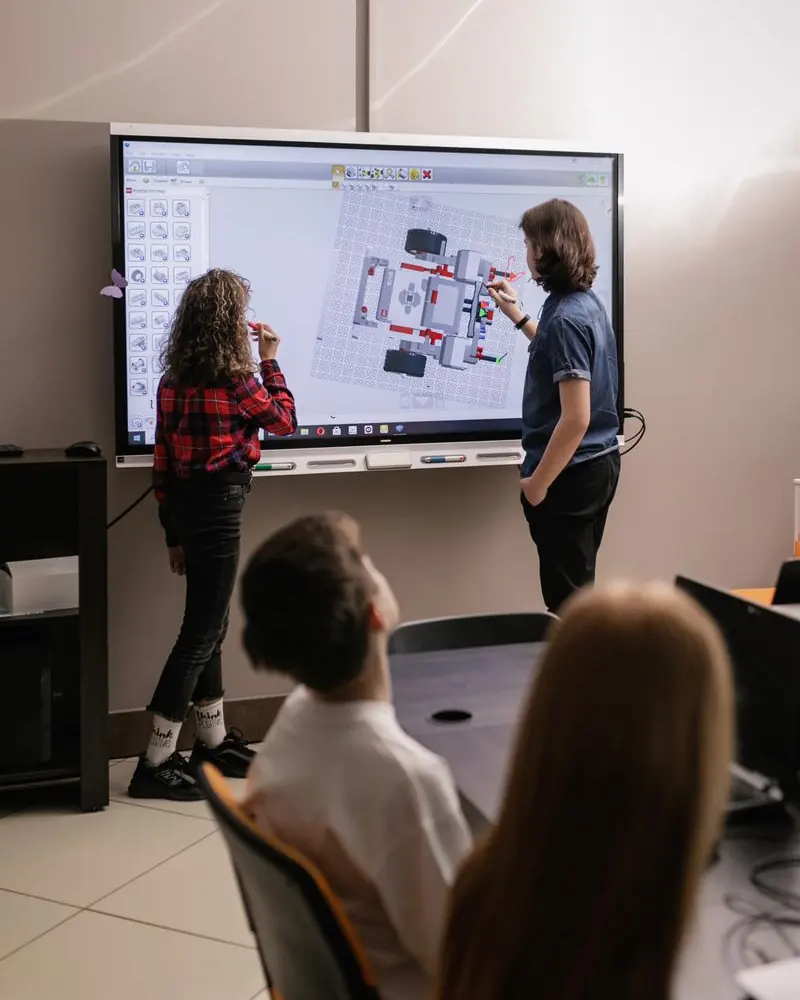 A student presenting her team's work at a smart board