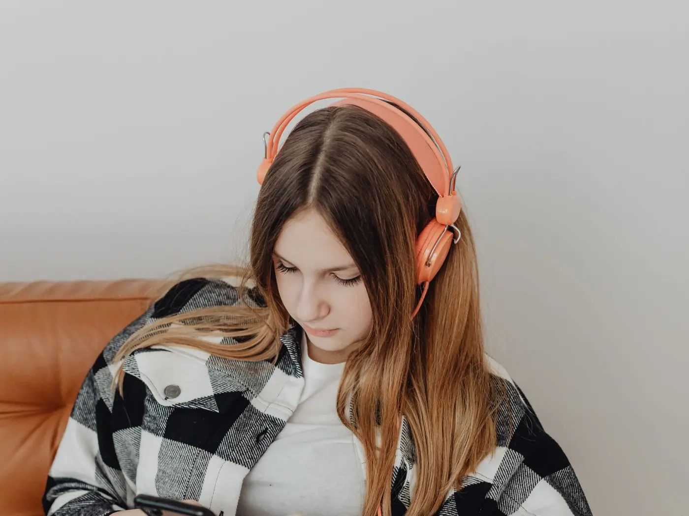 A teenage girl in headphones checking her phone