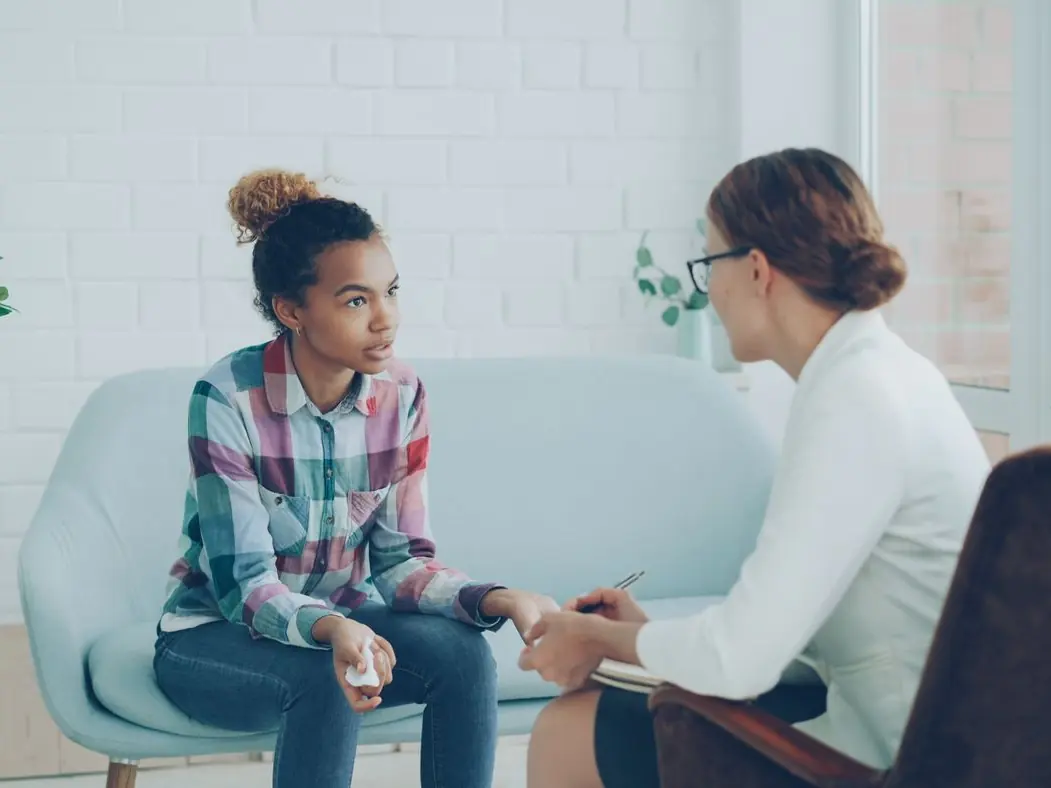 A teenage student talking with a counselor in a bright office